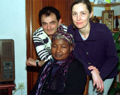 Beatrice, sentada, junto a la pareja que la ha acogido en su casa de Granada.