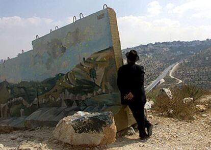 Un judío ultraortodoxo mira la ciudad palestina de Beit Jala en Cisjordania desde el muro que proteje el asentamiento judío de Gilo.