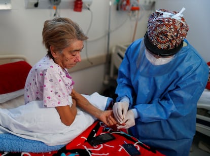 Una médica toma una muestra de sangre a una enferma grave de covid en un hospital a las afueras de Buenos Aires (Argentina).