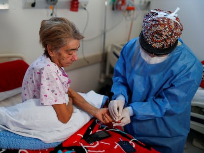 Una médica toma una muestra de sangre a una enferma grave de covid en un hospital a las afueras de Buenos Aires (Argentina).