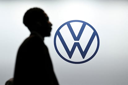 Un hombre pasa enfrente del logo de Volkswagen.