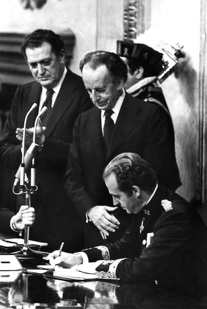 Juan Carlos I firma la Constitución en el Congreso de los Diputados, el 27 de diciembre 1978, ante Antonio Hernández Gil, presidente de las Cortes (centro), y Fernando Álvarez de Miranda, presidente del Congreso.
