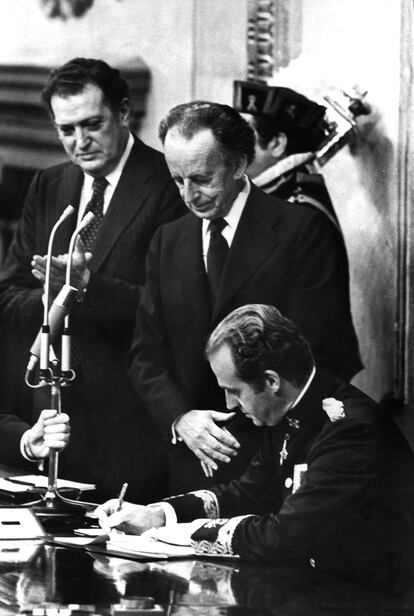 Juan Carlos I firma la Constitución en el Congreso de los Diputados, el 27 de diciembre 1978, ante Antonio Hernández Gil, presidente de las Cortes (centro), y Fernando Álvarez de Miranda, presidente del Congreso.