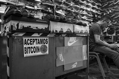 Un hombre espera clientes en una zapatería con un cartel que reza que acepta Bitcoins como pago en una imagen tomada el 15 de junio de 2022 en San Salvador. 