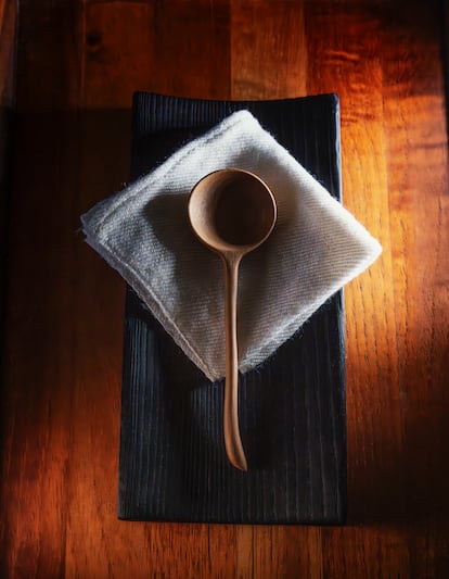 A spoon made from walnut wood on a charred ash tray.