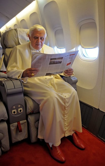 No eran Prada. Después de años de especulaciones sobre si los zapatos rojos eran de la marca de lujo o no, 'L'Osservatore Romano' desmintió que el Papa calzara de Prada. En la imagen, Benedicto XVI lee la prensa a bordo del vuelo que le lleva a Australia, el 12 de julio de 2008.