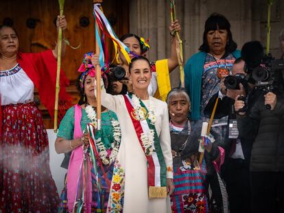 Claudia Sheinbaum sostiene el bastón de mando entregado por una comitiva de mujeres indígenas y afroamericanas, en la explanada del Zócalo capitalino.