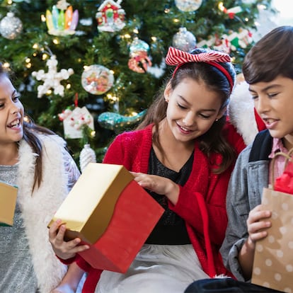 Niños y niñas de 12 años abriendo regalos en Navidad.