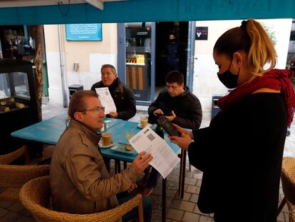 Una camarera pide certificado a los clientes en una mesa en la terraza de un bar en Málaga.