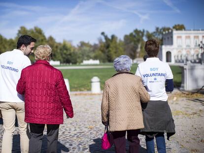 Dos voluntarios acompa&ntilde;an a personas mayores.