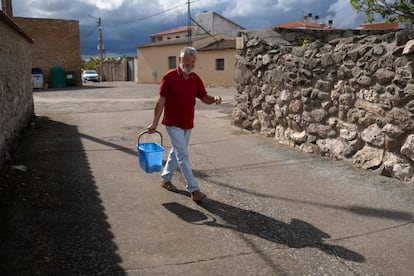 Un vecino de Juzbado carga con un cubo de agua por las calles del pueblo, el 13 de mayo.
