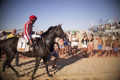 Bañistas de la playa de Sanlúcar contemplan a uno de los caballos ganadores de una de las carreras.
