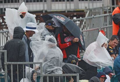 Los aficionados se resguardan de la lluvia.