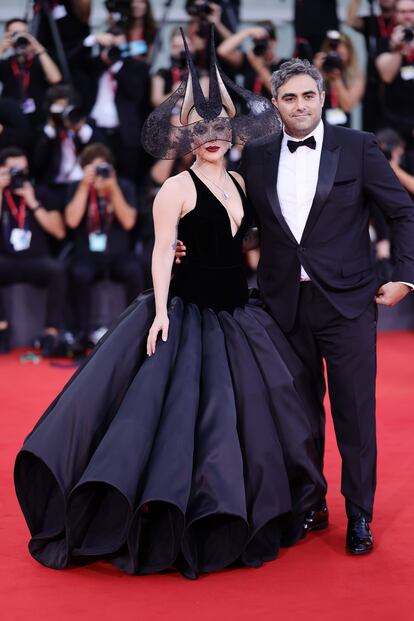 En ocasiones, arriesgarse no sale bien, y eso es lo que le pasó a Lady Gaga en la Mostra de Venecia. Puede que Gaga sea sinónimo de drama e impacto sobre la alfombra roja, no siempre de acierto. Para la 'première' de 'Joker', Gaga eligió un diseño escultural en negro de Dior con un escote pronunciado y una falda voluminosa festoneada que acababa en un bajo rematado con enormes ondas. Su tocado, igual de teatral, es una pieza 'vintage' del sombrerero Philip Treacy, concretamente de su colección de alta costura otoño/invierno 2001. En cuanto a las joyas, lució piezas brillantes de Tiffany & Co.: un collar de platino y oro amarillo de 18 quilates con diamantes, así como pendientes de diamantes y una pulsera Victoria.
