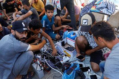 Palestinos desplazados cargan su móvil en el refugio de Naciones Unidas, este jueves en Jan Yunis.