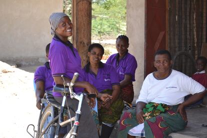 Louise, manager en Msitu Wa Tembo de la tienda de alquiler de bicicletas, descansa apoyada en una bici frente a otras mujeres de la comunidad.