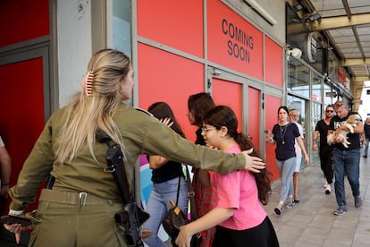 Una soldado israelí urge a civiles a refugiarse tras una alerta por lanzamiento de misiles en Ashdod, sur de Israel. 