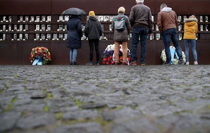 Vários visitantes depositam flores em frente aos retratos dos mortos que tentaram chegar a Berlim Ocidental, no Memorial do Muro na capital alemã.