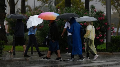 Varias personas se protegen de la lluvia en Palma de Mallorca, donde este martes ha llegado un temporal de lluvia y viento.