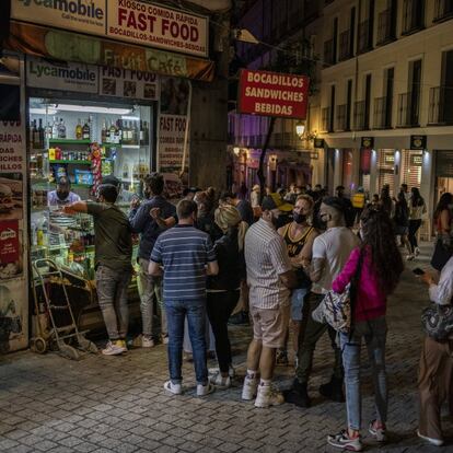 Varias personas hacen cola en una tienda de alimentación del centro de Madrid pasadas las 23:00 horas.