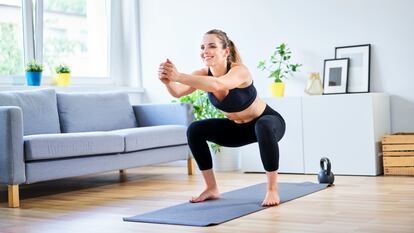 A woman does squats at home.