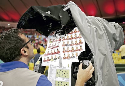 Um operador de câmera brasileiro acompanha o jogo entre Espanha e Chile na Copa do Mundo de 2014 com os mapas das posições dos jogadores sobre o campo. Mesmo na era digital, os profissionais ainda preferem usar folhas de papel presas com fita adesiva para controlar quem faz cada jogada. 