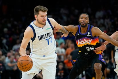 Luka Doncic, de blanco, conduce el balón ante Mikal Bridges, de los Phoenix Suns.