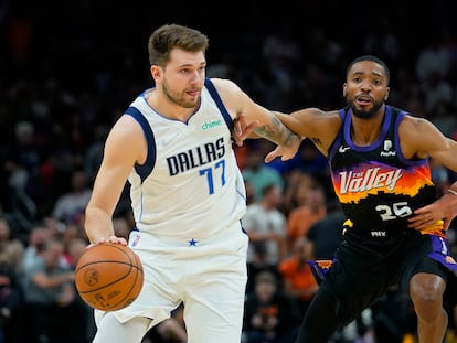 Luka Doncic, de blanco, conduce el balón ante Mikal Bridges, de los Phoenix Suns.