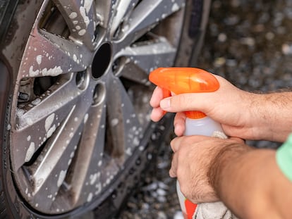 Limpiando llantas de un coche con un limpiador en spray.