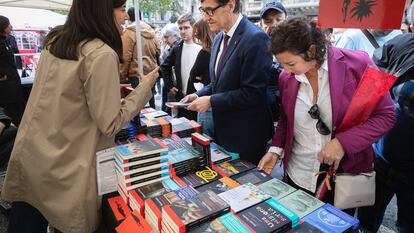 El primer secretario del PSC, Sañvador Illa, junto a la portavoz parlamentaria Alícia Romero, conversa con una librera en una parada de Sant Jordi. / PSC