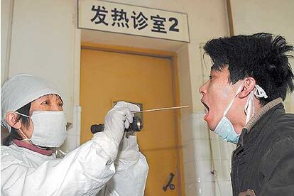 Un mdico chino hace una prueba de la gripe aviar a un paciente en Shangai.