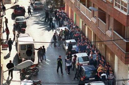 Cola de clientes que esperan comprar droga en una calle del distrito marítimo de Valencia. La fotografía, de 2001, forma parte de la exposición de fotoperiodismo de la Unió de Periodistes Valencians.