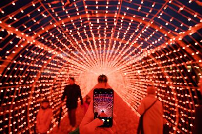 Un hombre saca una fotografía con su móvil en el túnel de luz más largo de Europa, compuesto por 28.750 estrellas colocadas en 25 aros y 1.150 guirnaldas, el 25 de noviembre de 2017, en Suiza.