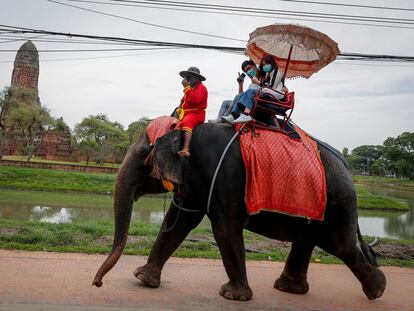 Dos turistas sobre un elefante en la ciudad de Ayutthaya, Tailandia, el pasado 14 de junio.