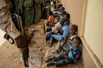 Un guardia vigila en los alrededores de la escuela de la aldea de Inizdan, en el oeste de Níger, mientras los niños se refugian del calor a la sombra de sus paredes y esperan a sus padres, que participan en una reunión con agentes del Gobierno. Los vecinos de este pequeño asentamiento se lamentan de la falta de oportunidades para sus jóvenes en un contexto de violencia y cambio climático que provoca sequías y lluvias irregulares. Casi todo el pueblo vive del cultivo de cereales.