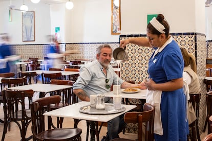 Una mesera sirviendo un café lechero a  comensales en la churrería El Moro.