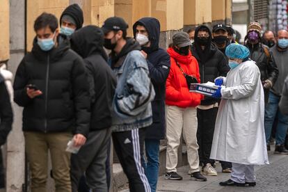 Una sanitaria atiende a personas haciendo cola para realizarse una PCR frente al centro de salud Universidad, en Malasaña, Madrid