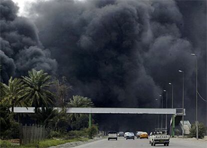 Varios vehículos circulan por una de las carreteras de Bagdad bajo el intenso humo negro que desprende el petróleo incendiado en los alrededores de la ciudad.