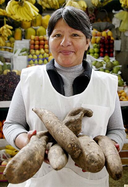 Una mujer muestra unas aricomas o yacones en un mercado de Lima.