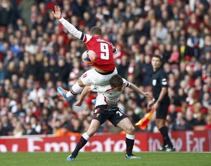 Lukas Podolski lucha por el balón junto a Joe Allen, del Liverpool.