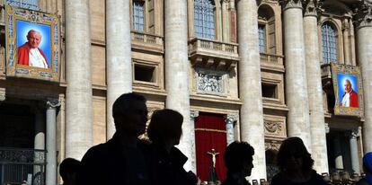 En la imagen, un grupo de personas miran tapices con sendos en los balcones de la basílica de San Pedro en el Vaticano, donde tendra lugar la ceremonia de canonización.