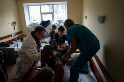El doctor Yurii Kuznetsov, a la izquierda, ayuda a las enfermeras a trasladar a un paciente anciano al hospital de Izium, Ucrania, el 17 de septiembre de 2022. 