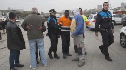 En el centro de la imagen, con un anorak naranja, uno de los tripulantes rescatados. De espaldas, el propietario de la embarcación.