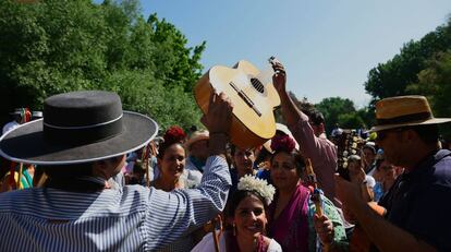 Un peregrino pasa una guitarra a un romero para cantar sevillanas.