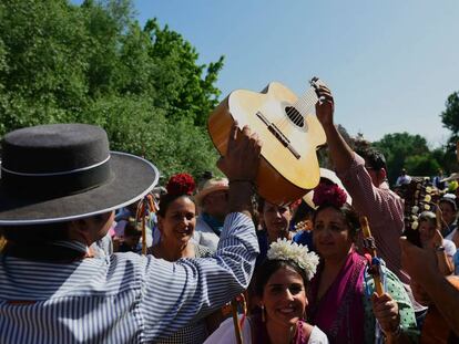 Un peregrino pasa una guitarra a un romero para cantar sevillanas.