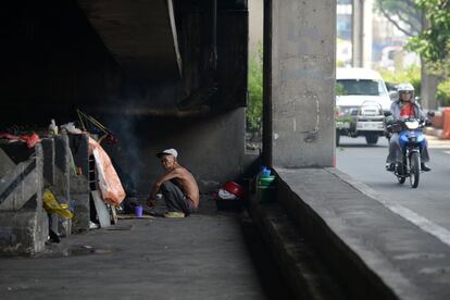 An elderly man prepares a hot drink under a bridge, where he is temporarily living, in Manila on May 18, 2017.