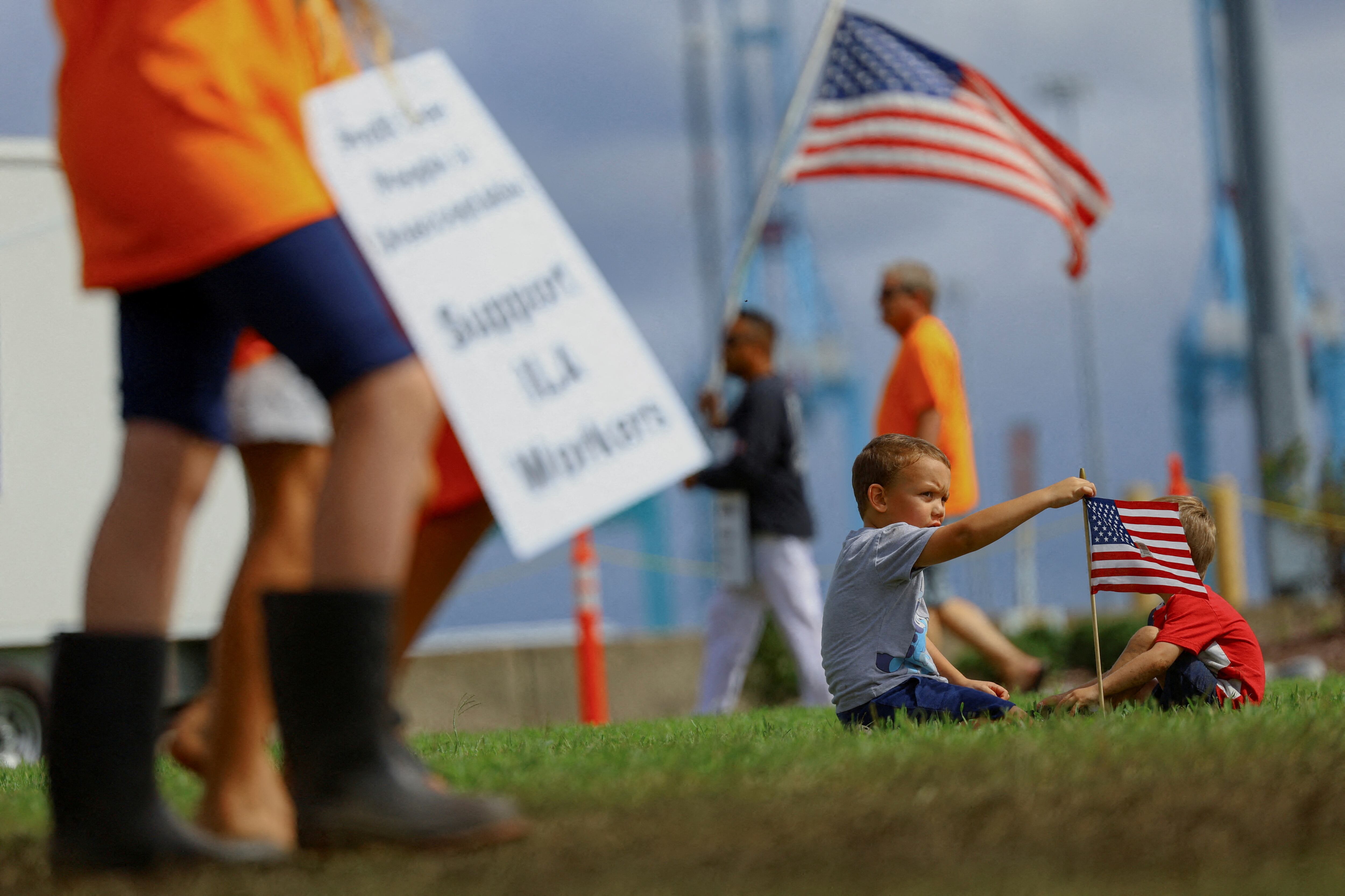 Dos niños juegan con una bandera mientras estibadores de la ILA se manifiestan en Portsmouth (Virginia), este miércoles.