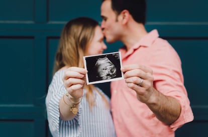 Una pareja muestra la ecografía de su hijo.