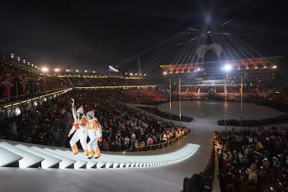 Seo Soonseok e Kim EunJung caminham com a tocha olímpica durante a cerimônia de abertura