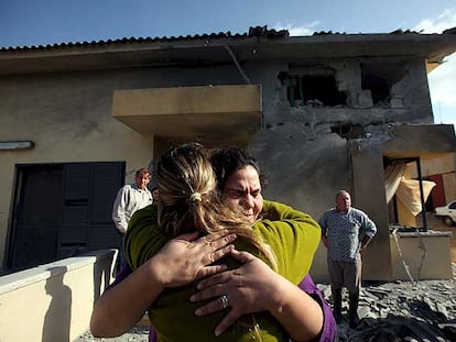 Dos mujeres se abrazan delante de una casa dañada el 24 de diciembre por un cohete palestino en Tequma, en el sur de Israel.